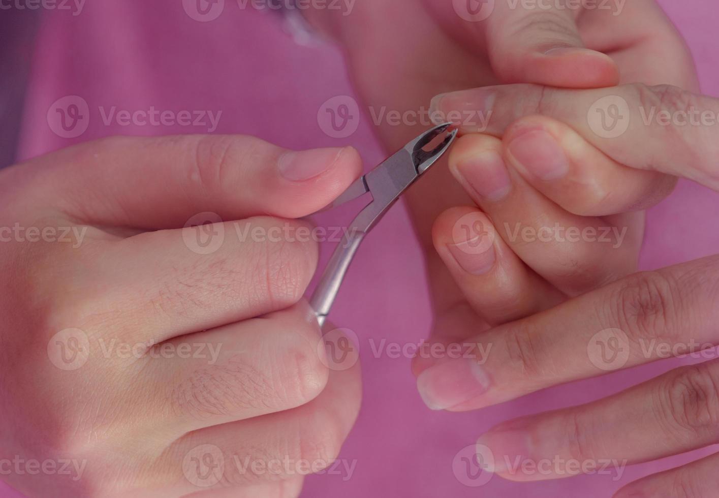 donna che riceve un servizio di manicure per unghie da parte di un manicure professionista presso il salone di bellezza. l'estetista usa il tagliacapelli per pulire e tagliare la cuticola nel salone per unghie e spa. terapia delle mani e delle unghie da parte del terapista. foto