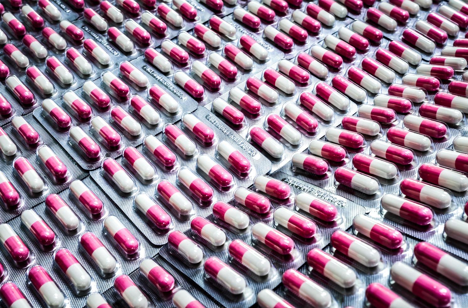 capsule antibiotiche rosa-bianche in blister. resistenza ai farmaci agli antibiotici. industria dell'imballaggio farmaceutico. assistenza sanitaria globale. sfondo della farmacia. prodotto farmaceutico. linea di produzione. foto