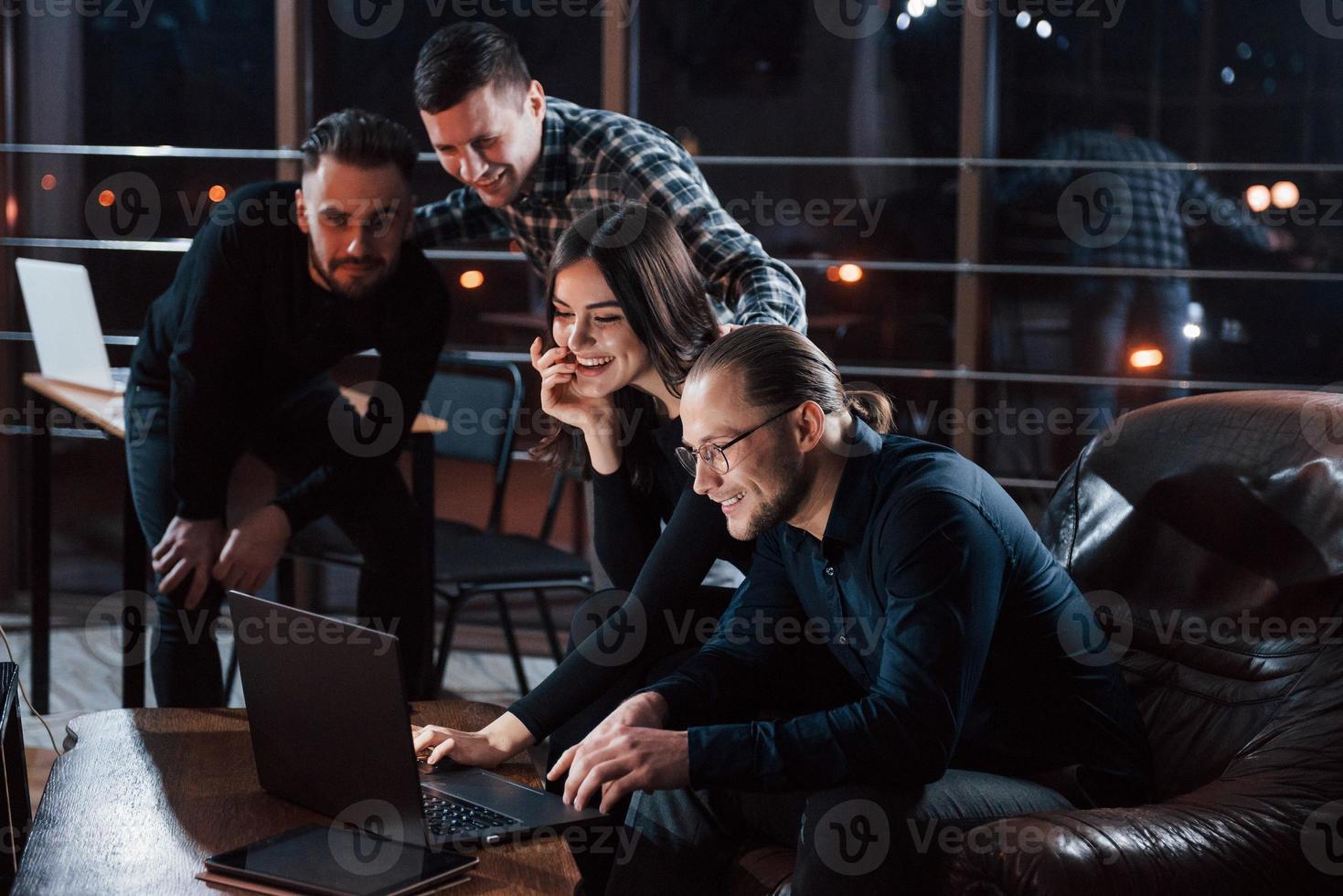 vittoria e successo. team di giovani imprenditori lavora al loro progetto di notte in ufficio foto