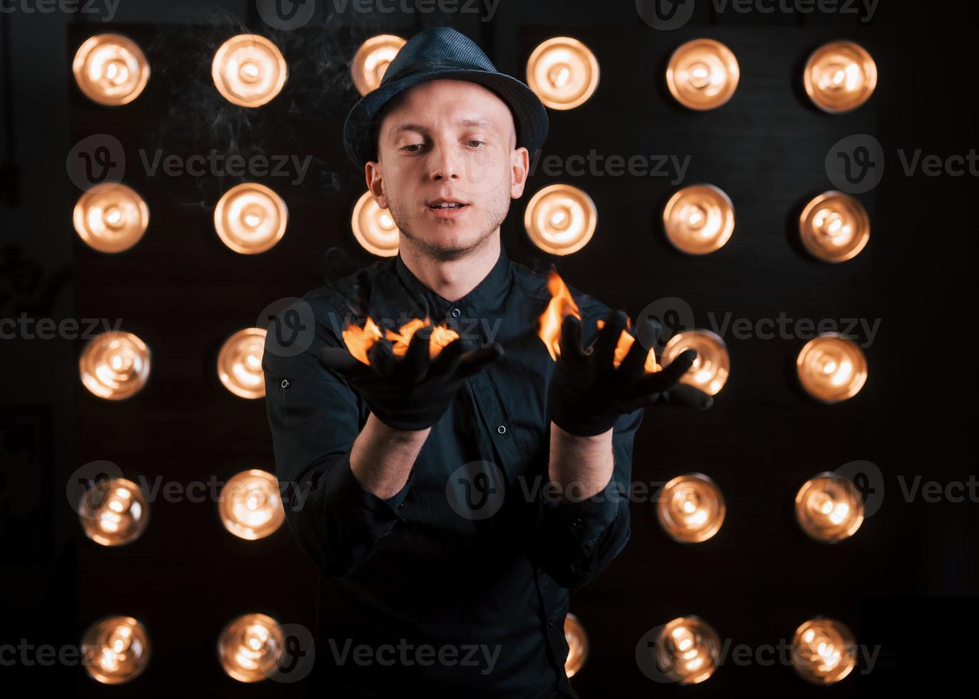 controllare il processo di masterizzazione. illusionista professionista in cappello nero, camicia e guanti che giocano con il fuoco foto