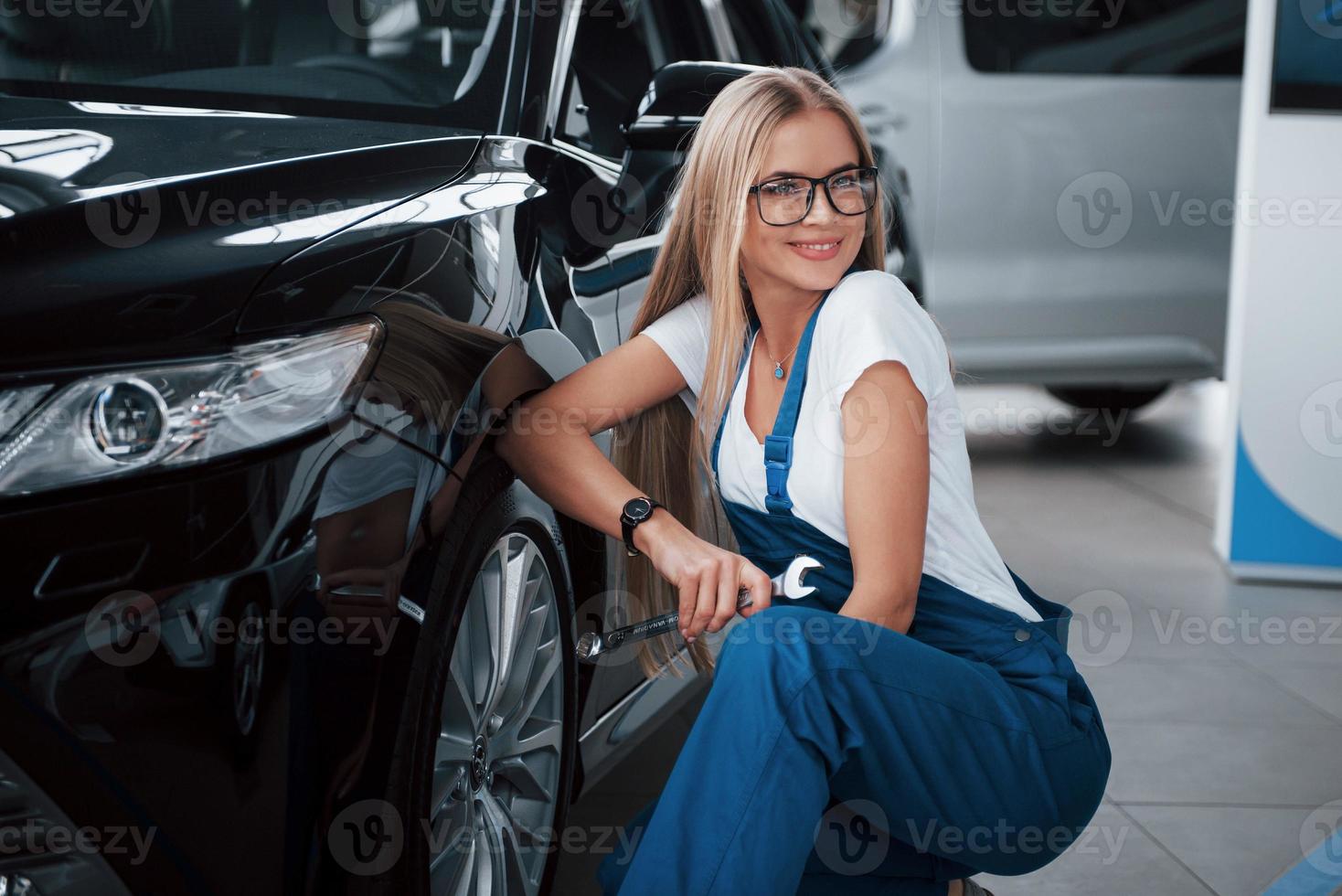 seduto vicino alla ruota anteriore di una nuova auto di lusso perfettamente lucidata foto