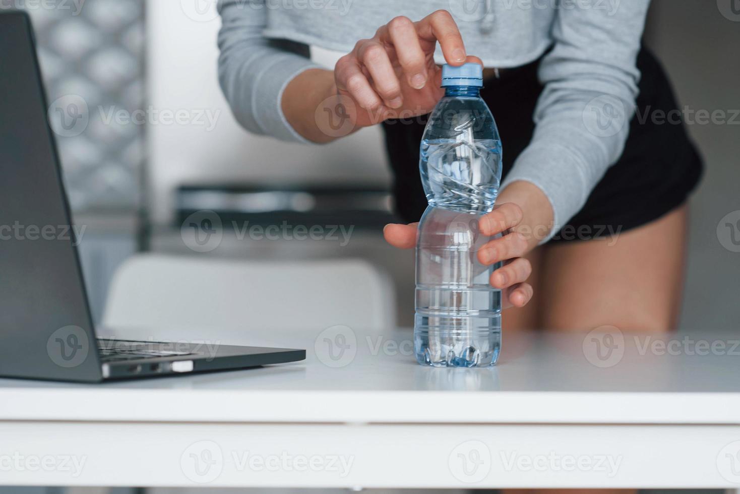 apertura bottiglia d'acqua. ragazza nella cucina moderna a casa durante il fine settimana al mattino foto