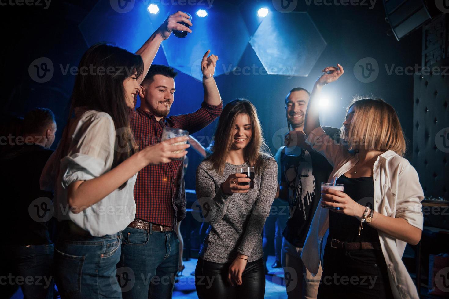 la ragazza è al centro dell'attenzione. persone felici che ballano nel night club di lusso insieme a diversi drink nelle loro mani foto