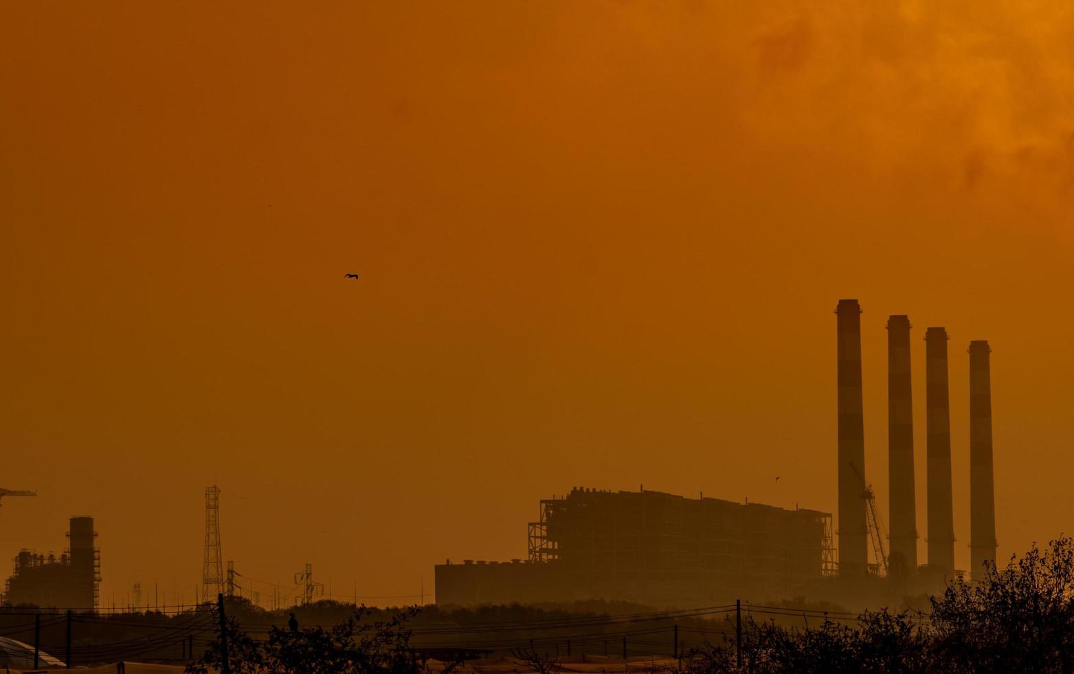 centrale elettrica con cielo al tramonto arancione e uccelli che volano nel cielo. concetto di inquinamento atmosferico. energia per fabbrica di supporto in zona industriale. potenza ed energia. polvere diffusa nell'aria la sera. foto