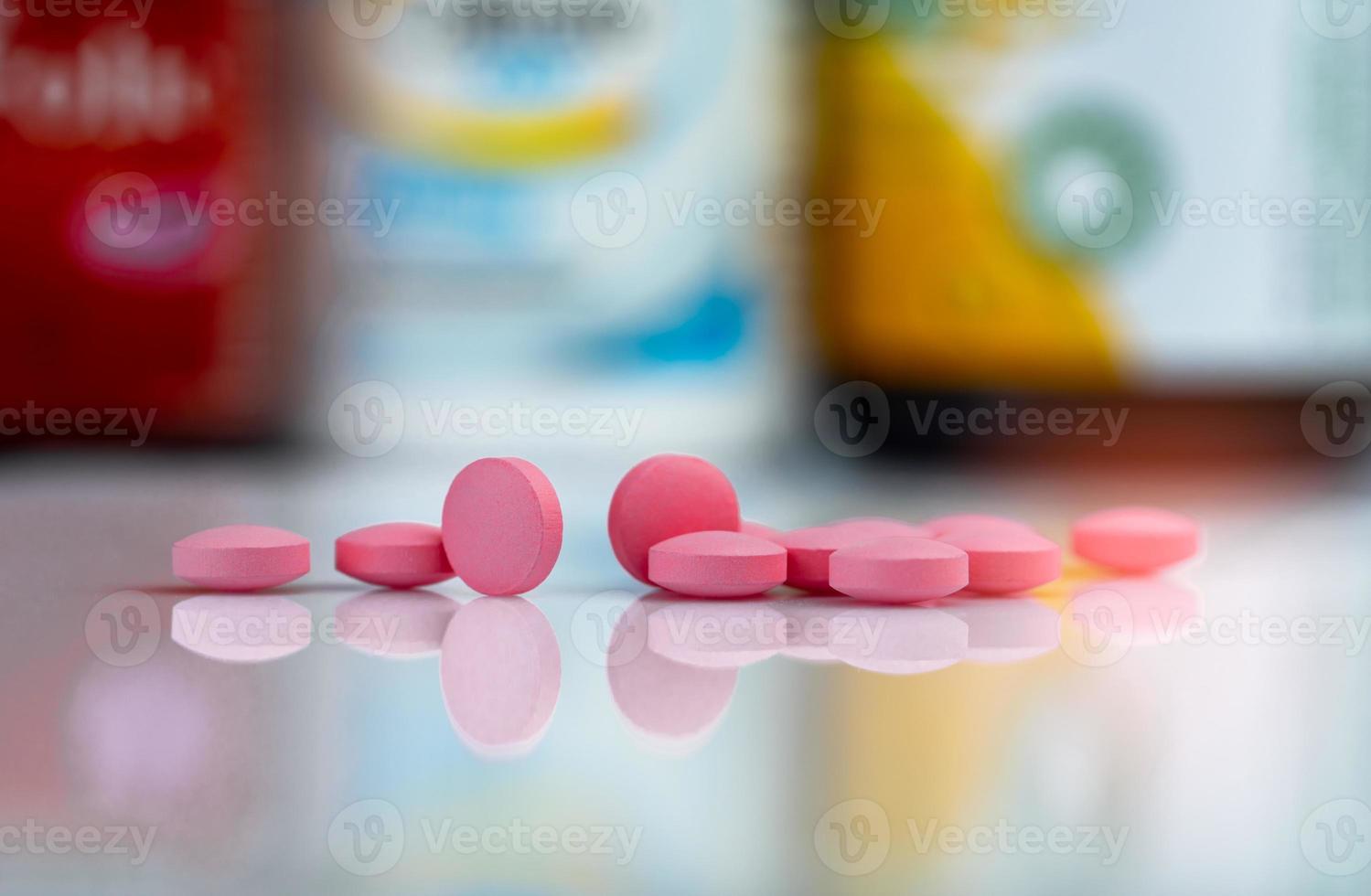 compresse rosa pillole su sfondo sfocato della scatola del farmaco e del flacone del farmaco. compresse di vitamine e integratori. farmacia farmacia. prodotti farmaceutici. sanitario e farmaceutico. riconciliazione dei farmaci. foto