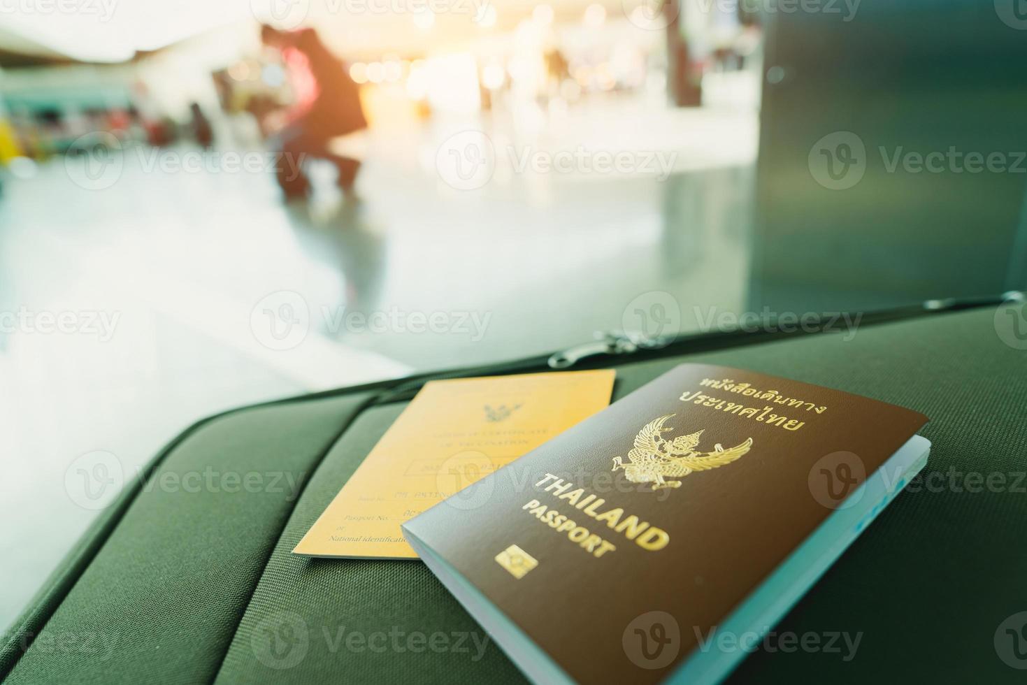 passaporto thailandese e passaporto vaccino sul bagaglio su sfondo sfocato del turista in aeroporto. certificato di vaccinazione per viaggiare durante l'epidemia di coronavirus. le parole tailandesi sono passaporto thailandese. foto