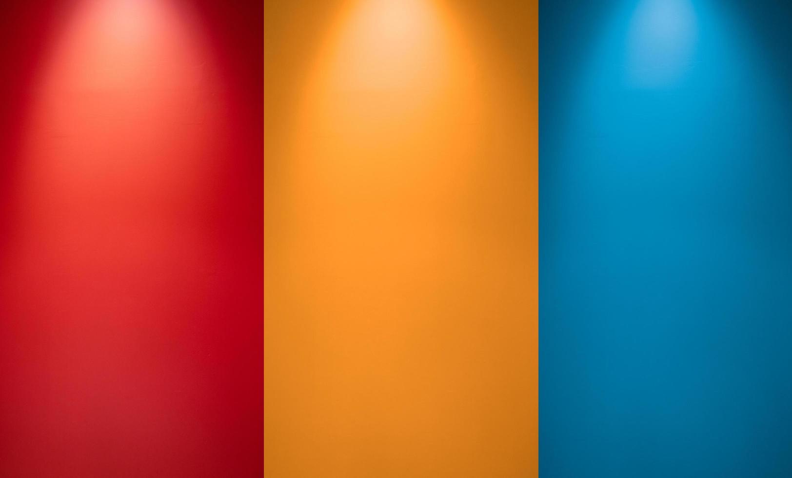 parete vuota rossa, arancione o gialla e blu con faretti. luce della lampada illuminata. interno della stanza con lampada da soffitto e parete colorata. sfondo di struttura della parete dello studio foto