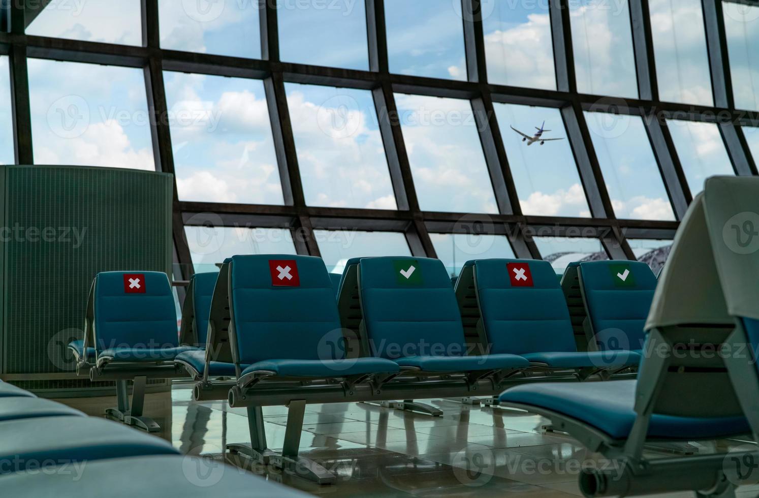 posto vuoto nella sala partenze del terminal dell'aeroporto. distanza per un posto mantenere la distanza per proteggere il coronavirus e la distanza sociale dei passeggeri per sicurezza. visto aereo volare attraverso la finestra di vetro. foto