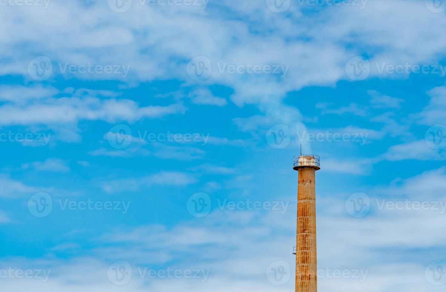 tubo di fumo arrugginito di fabbrica contro il cielo blu e nuvole bianche. fumo bianco dal camino del tubo industriale. aria pulita intorno alla fabbrica. gestione ambientale nello stabilimento di produzione. foto