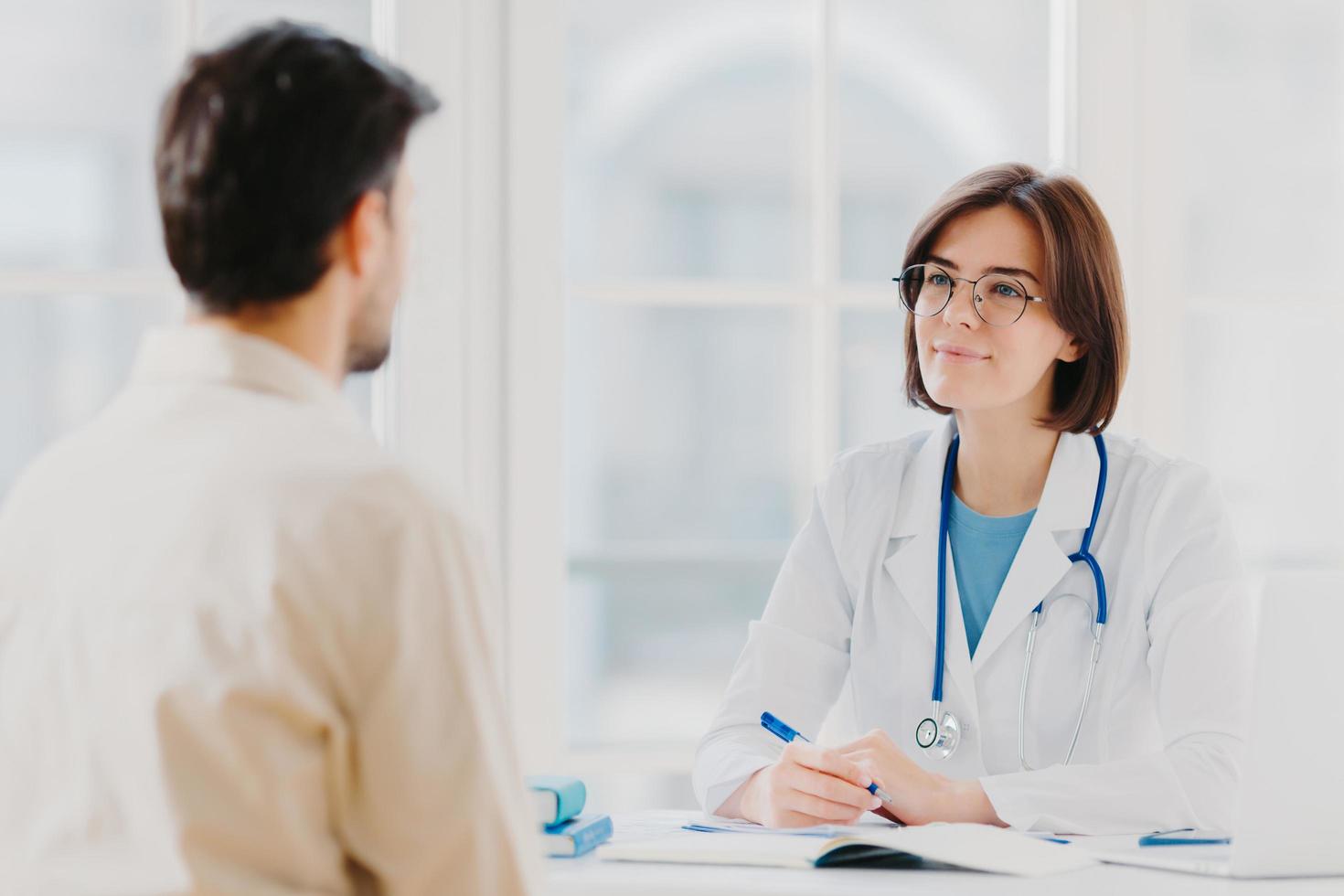 assistenza sanitaria, sessione di terapia e concetto di assistenza. la dottoressa professionista parla con un paziente maschio, fornisce consulenza e fa prescrizioni, scopre i sintomi della malattia, fornisce aiuto. foto