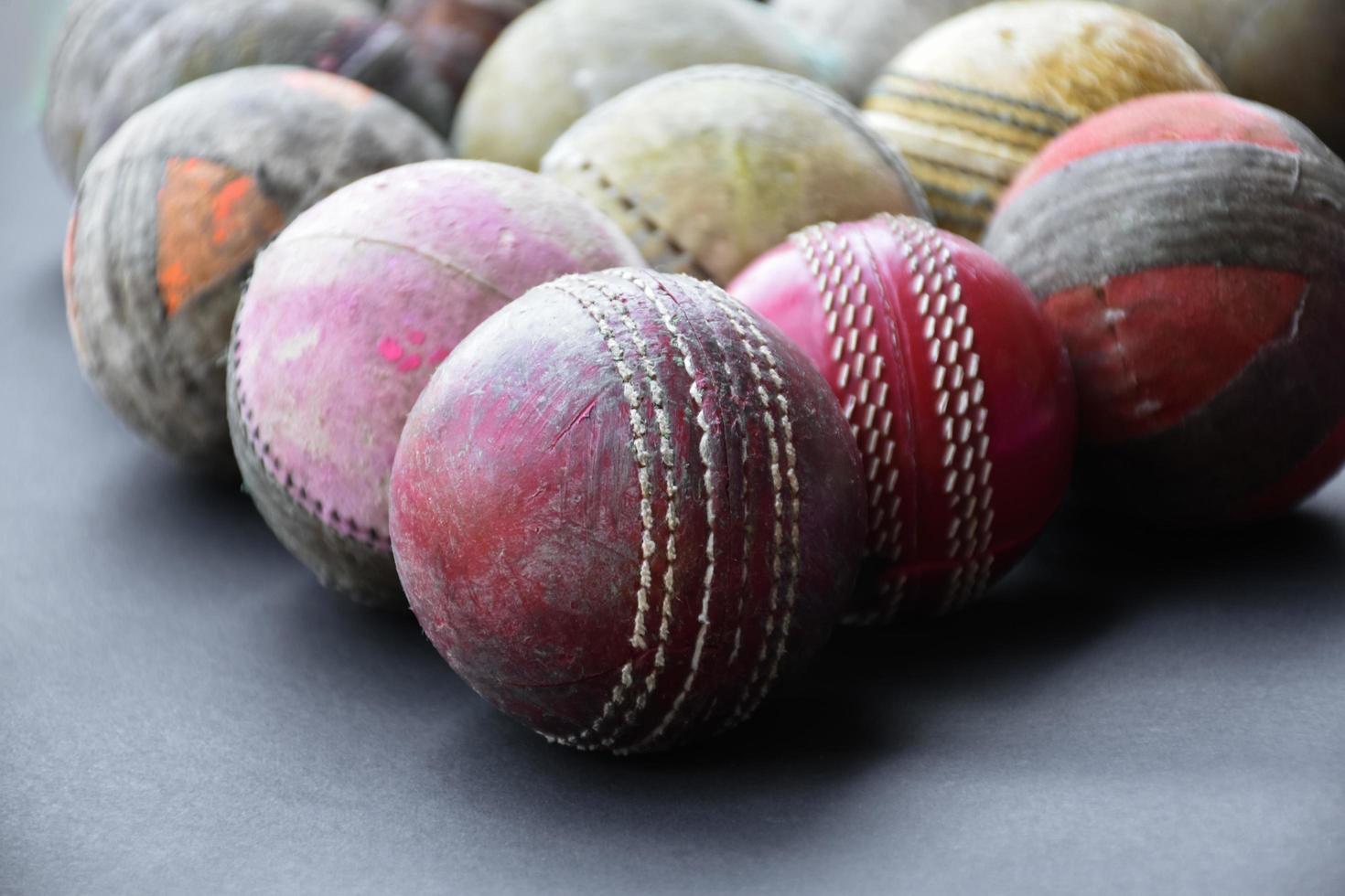 vecchie attrezzature per lo sport di cricket da allenamento su pavimento scuro, palla di cuoio, wicket, casco e mazza di legno, messa a fuoco morbida e selettiva, tradizionali amanti dello sport di cricket in tutto il mondo. foto