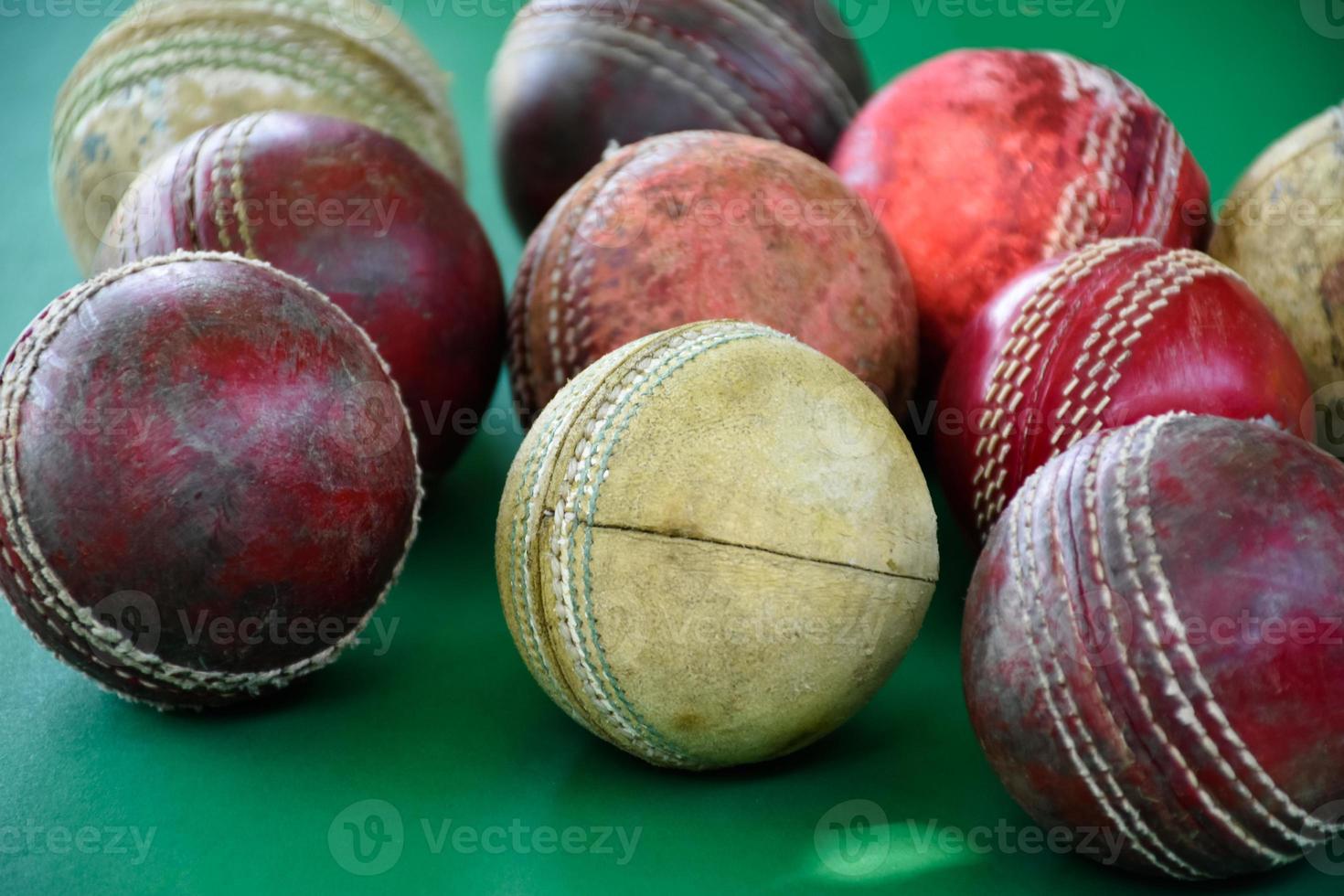 primo piano palle da cricket in pelle vecchie e usate sul pavimento verde, fuoco morbido e selettivo. concetto per gli amanti del cricket in tutto il mondo. foto