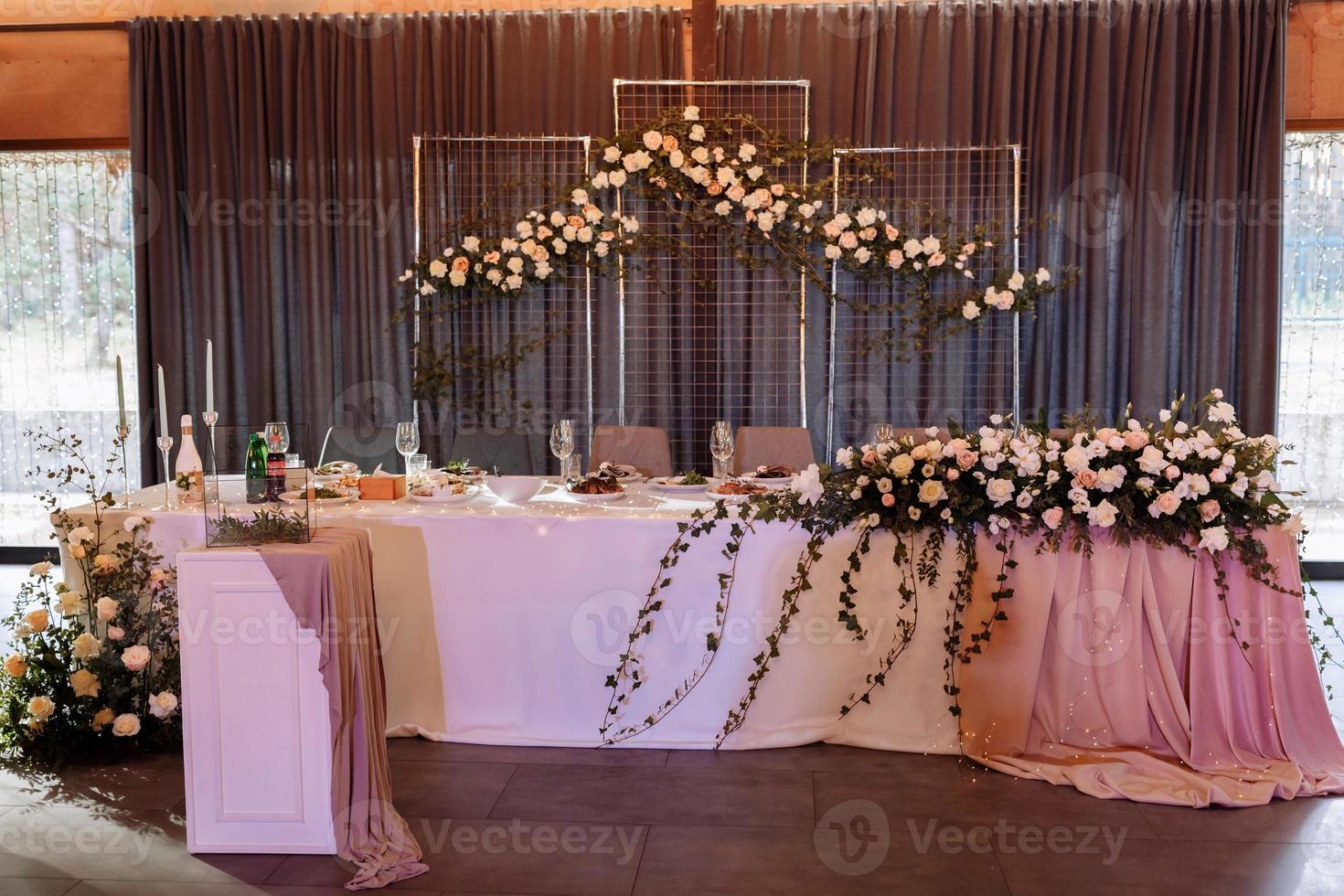 nozze. banchetto. la tavola festiva degli sposi e degli invitati, addobbata con una composizione di fiori bianchi e rosa e verde, ci sono le candele, servite con stoviglie in restarane foto