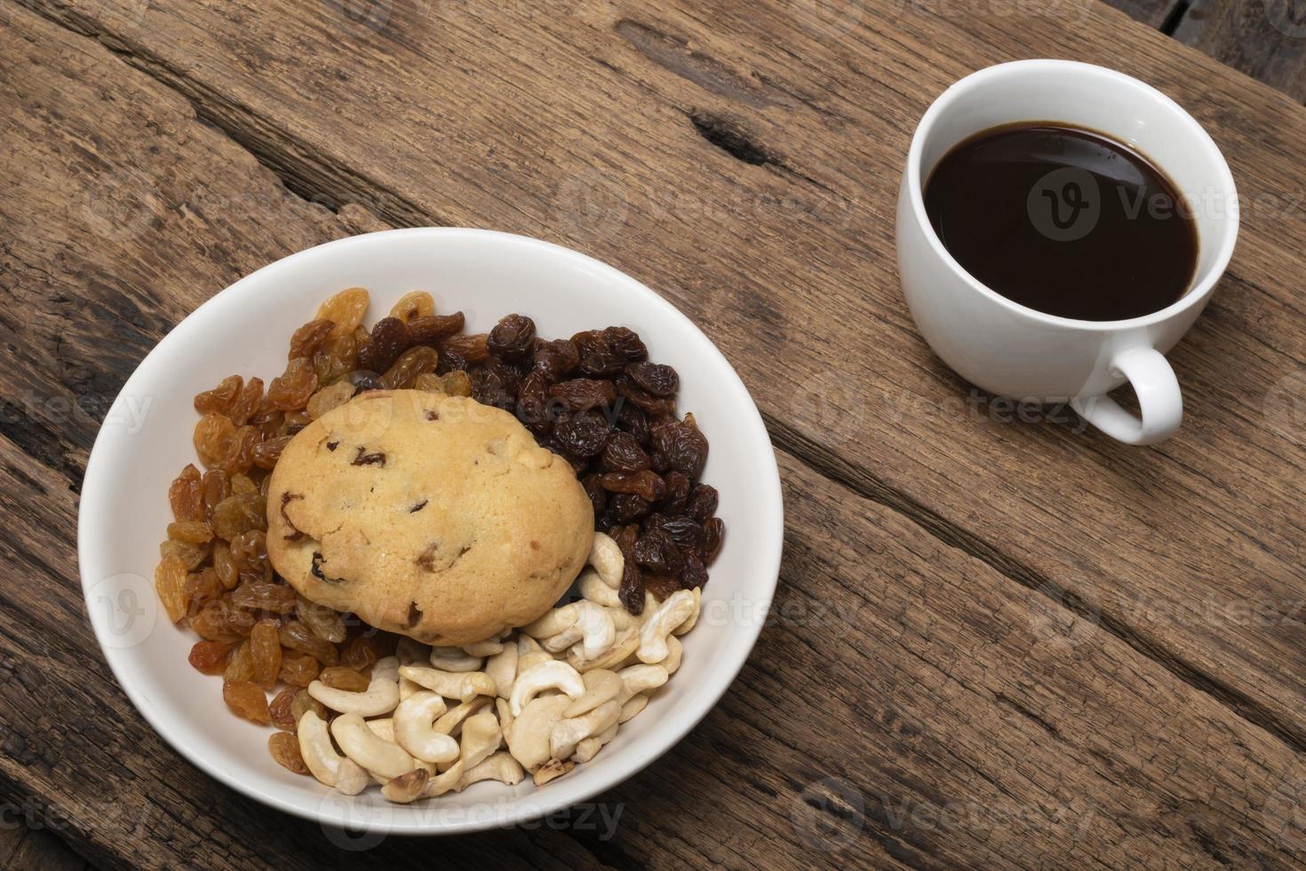 caffè nero anacardi uvetta biscotti in piatto sul tavolo di legno. foto