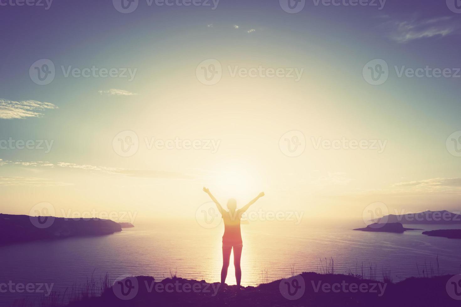 donna felice con le mani in alto sulla scogliera sul mare e sulle isole al tramonto foto