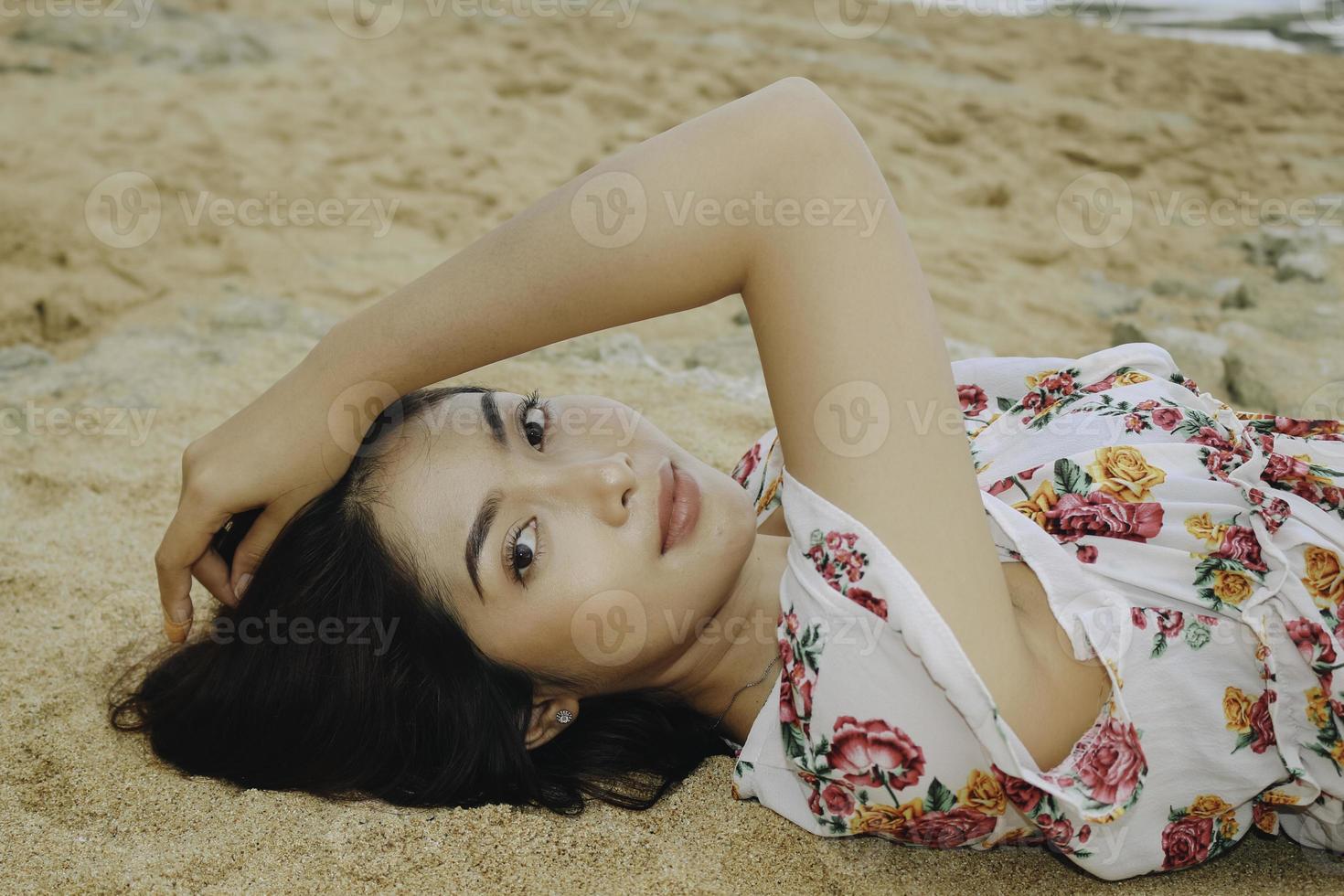 primo piano vista dall'alto di una donna sorridente sdraiata e rilassante sulla spiaggia di sabbia foto