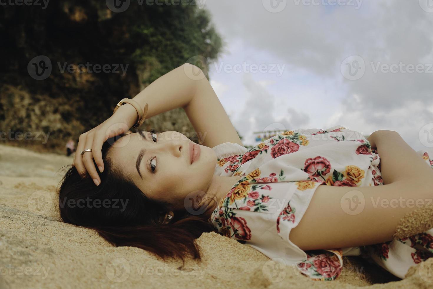 primo piano vista dall'alto di una donna sorridente sdraiata e rilassante sulla spiaggia di sabbia foto