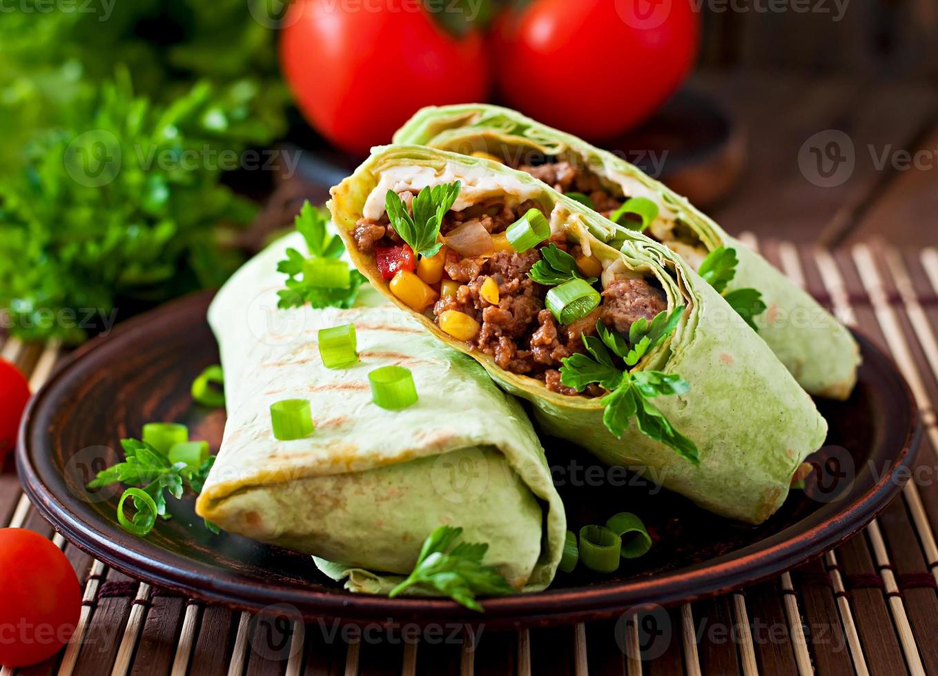 burritos avvolge con carne macinata di manzo e verdure su un fondo di legno foto