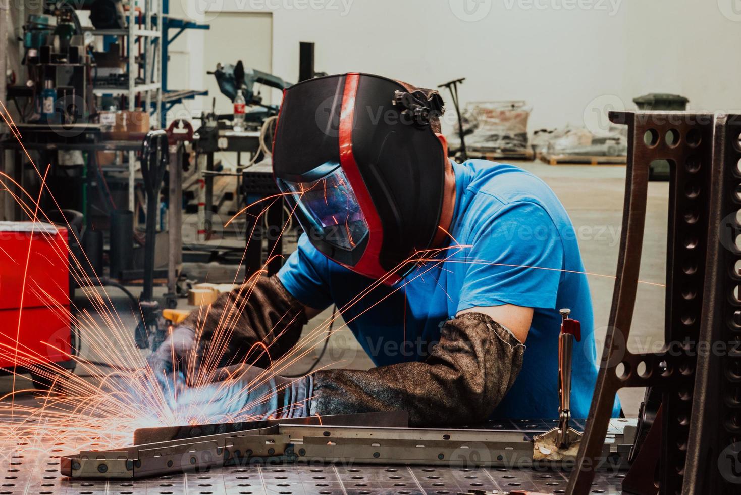 saldatore professionista dell'industria pesante che lavora all'interno della fabbrica, indossa il casco e inizia a saldare. messa a fuoco selettiva foto