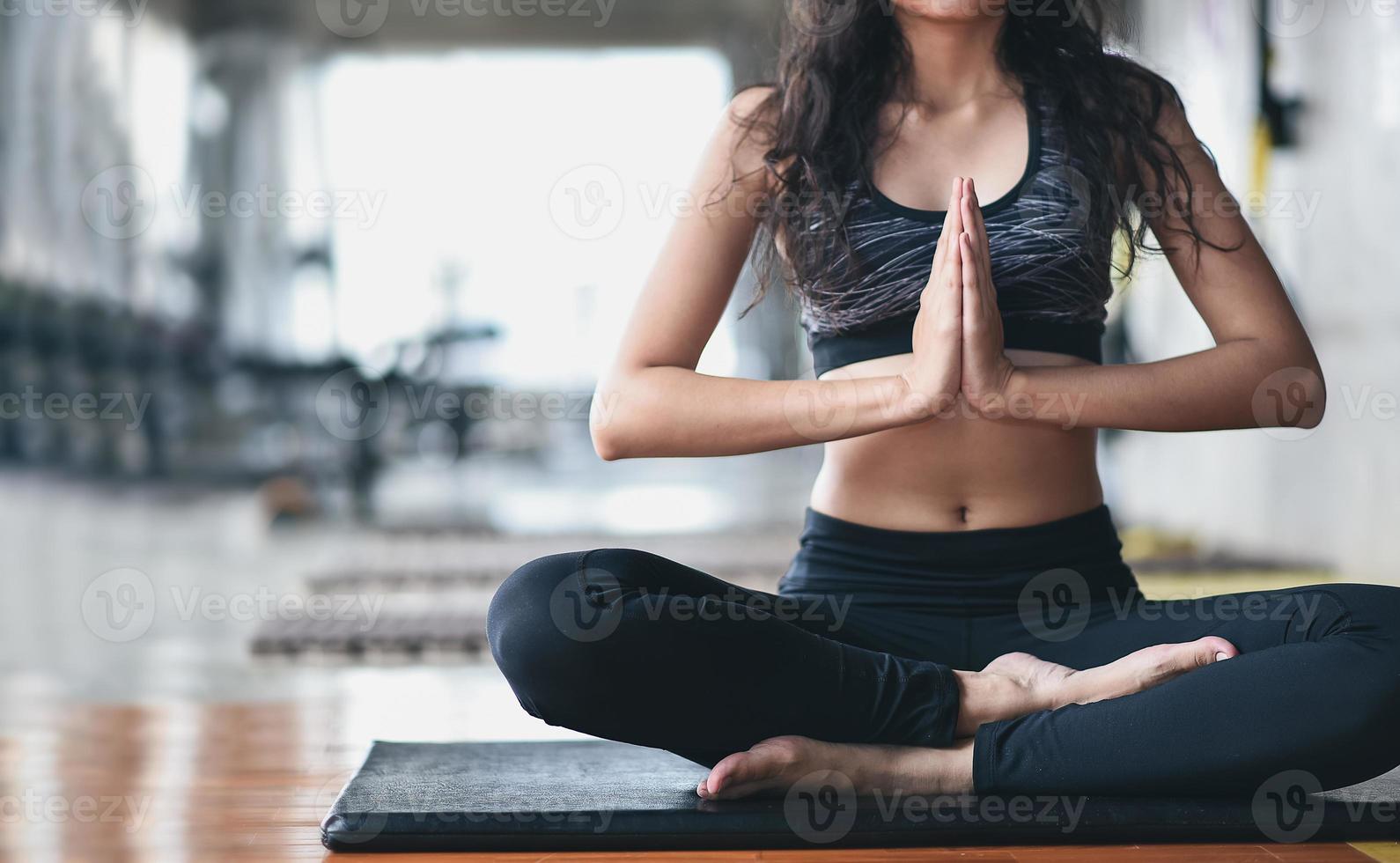 sport donna asiatica che pratica lezione di yoga, respirazione, meditazione, esercizio di ardha padmasana, allenamento in palestra foto