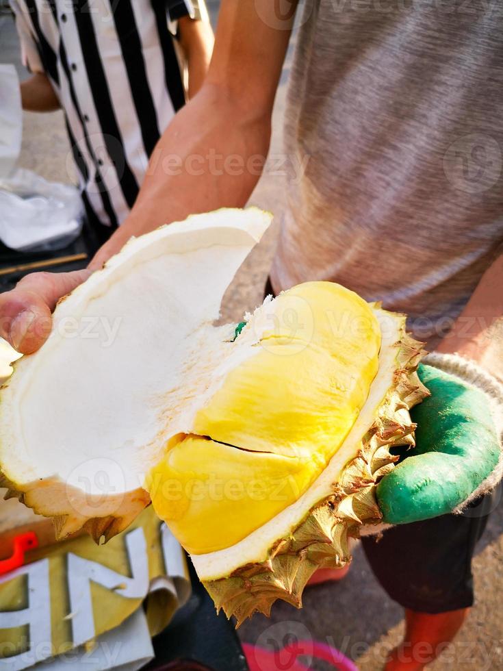 commerciante di bucce di durian per mostrare la polpa di durian che è matura, giallo dorato, pronta da mangiare. il re dei frutti della Thailandia popolare in estate foto