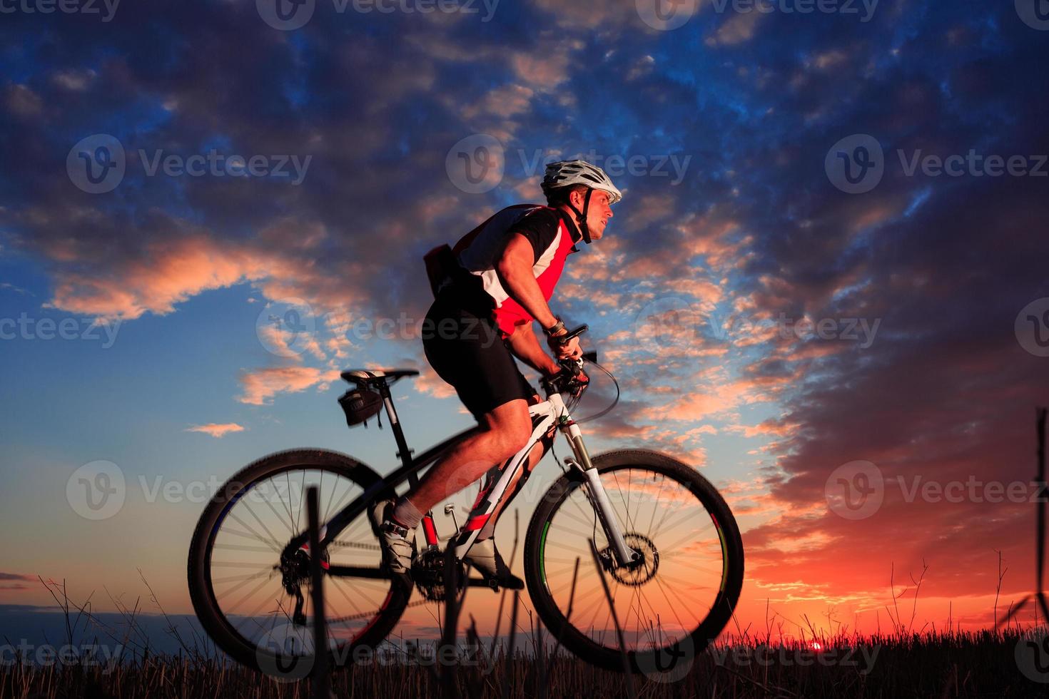 uomo con la bicicletta al tramonto all'aperto foto