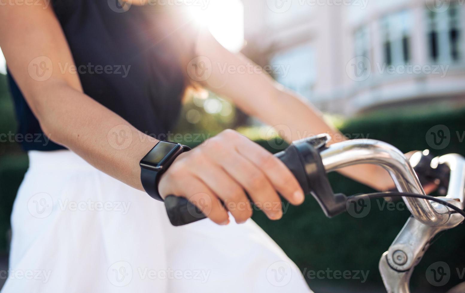 donna che guida la bici con uno smartwatch foto