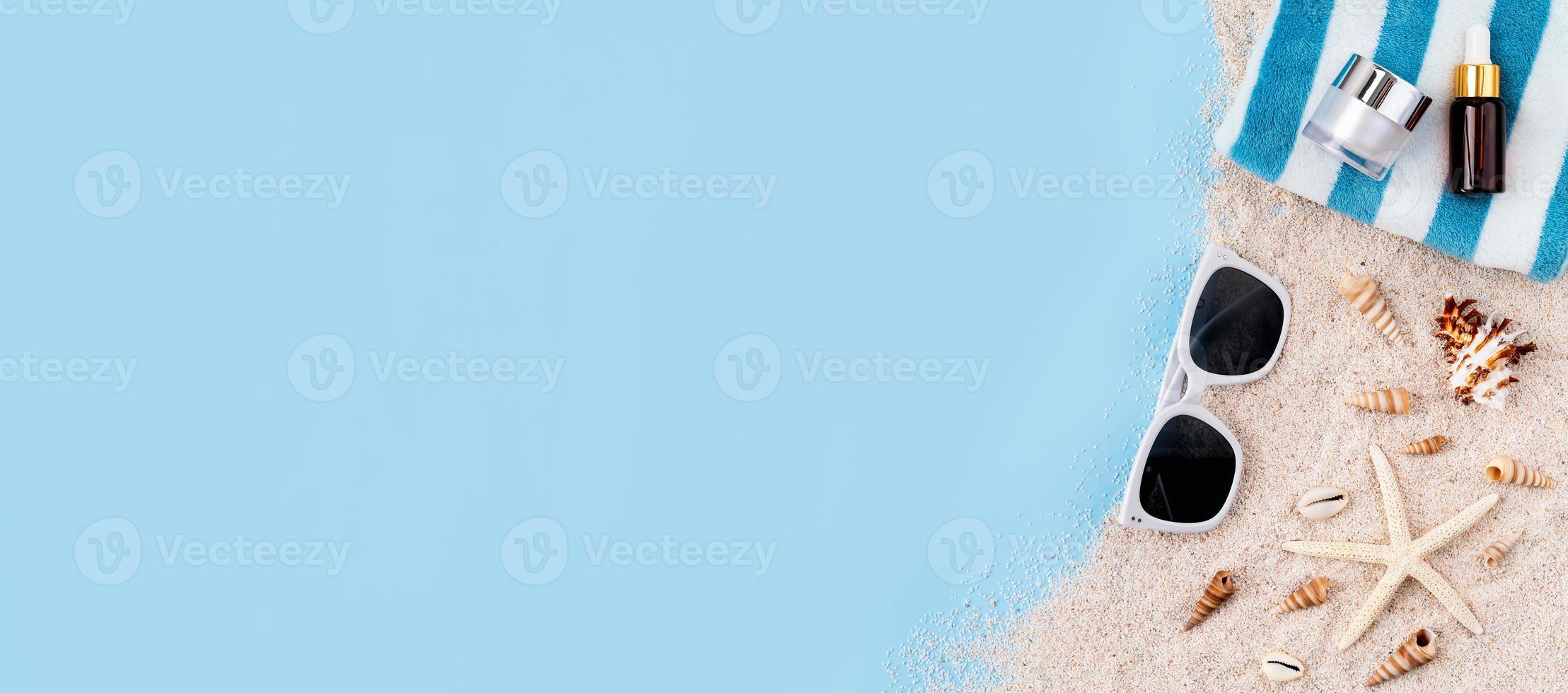 vista dall'alto con spazio per la copia della bottiglia di crema sulla sabbia con stelle marine e occhiali da sole su sfondo blu. foto