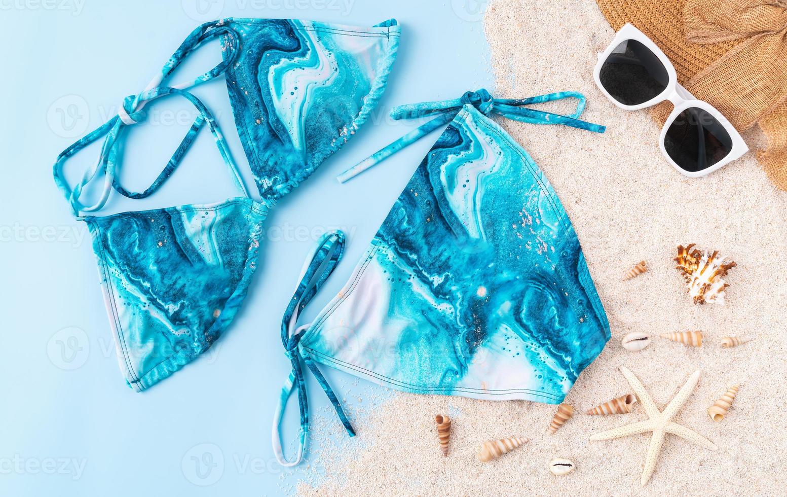 vista dall'alto di bikini e occhiali da sole, sandali con accessori da spiaggia su sfondo blu. concetto di ora legale. foto