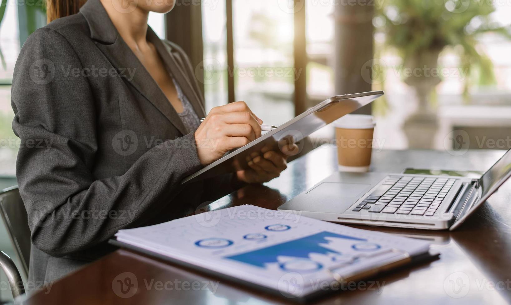 mano della donna di affari che lavora con il nuovo computer moderno e che scrive sul diagramma di strategia del blocco note come concetto foto