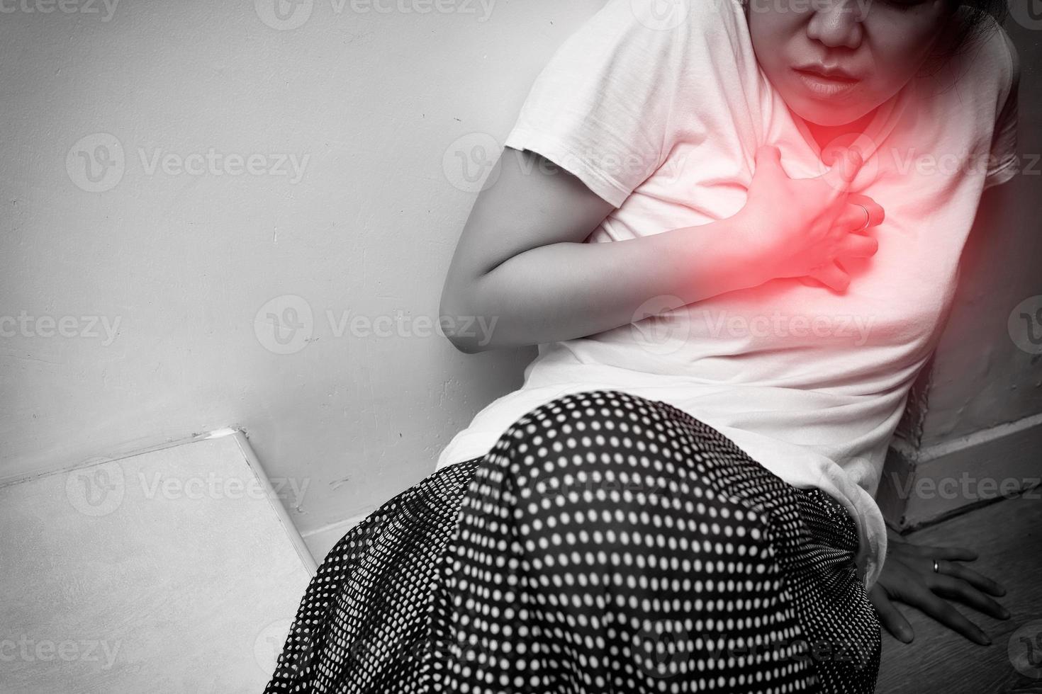 donna che ha infarto, dolore toracico o bruciore di stomaco da gerd, isolata su sfondo bianco con macchia rossa sul petto. tono bianco e nero. persone con problemi cardiaci o concetto di gerd foto