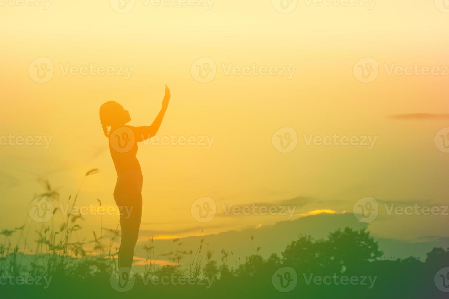 silhouette di donna che prega su sfondo bellissimo cielo foto