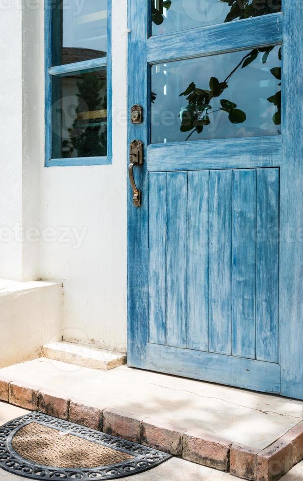 porta in legno blu con vecchio zerbino foto