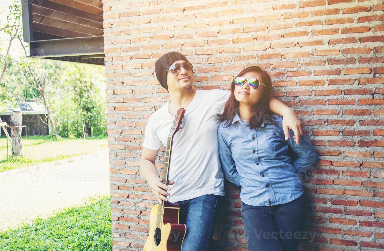 giovane hipster che suona la chitarra per rilassarsi durante le sue vacanze, godersi l'aria fresca e naturale. foto