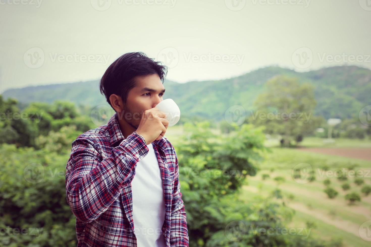 uomo barbuto bello hipster con una tazza di caffè mattutino che cammina nel parco. foto