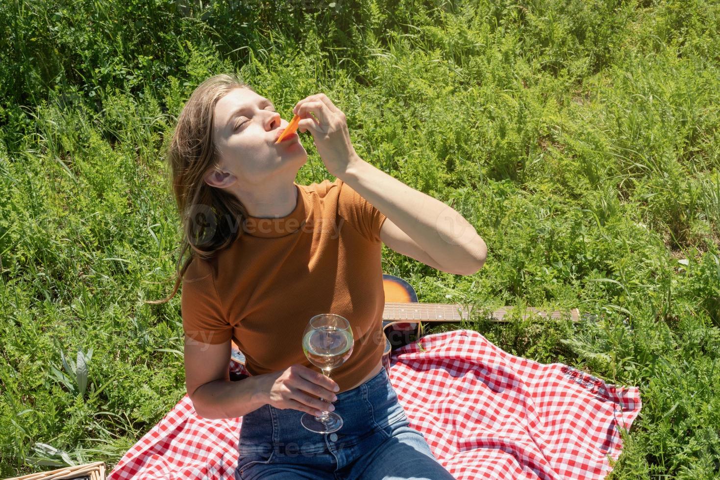 giovane donna nel parco fuori in una giornata di sole, godendosi l'estate sognando e bevendo vino foto