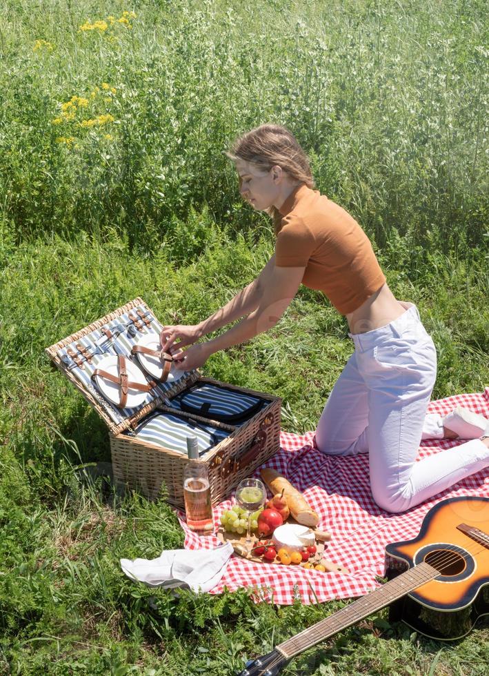 giovane donna caucasica che prepara un cestino da picnic all'aperto, pronta per un picnic foto