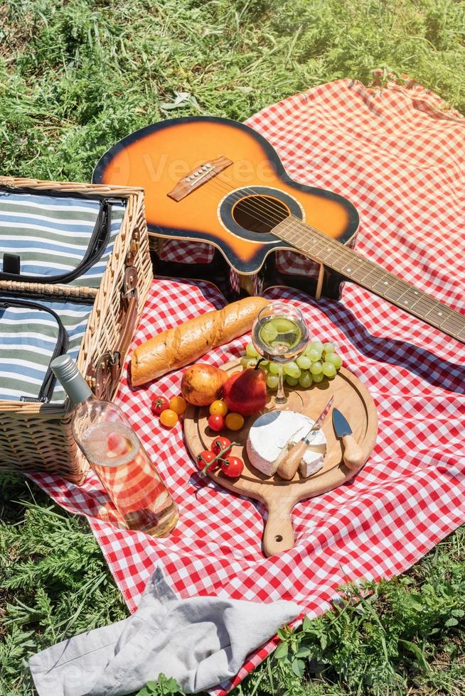 primo piano del cestino da picnic con bevande e cibo sull'erba foto