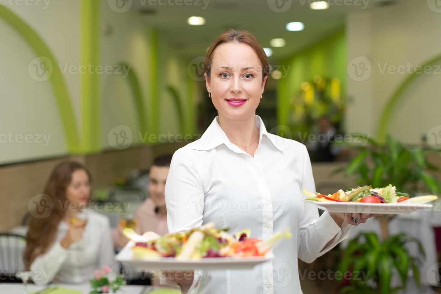 cameriere femminile che serve il tavolo degli ospiti foto