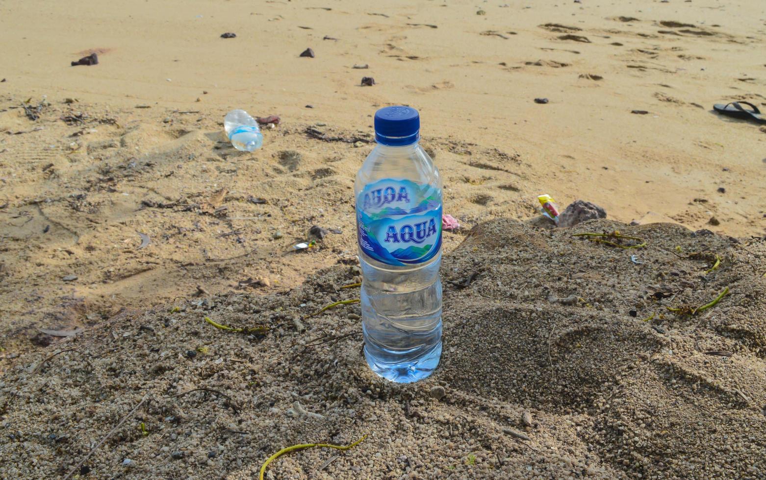 batam, indonesia, 5 maggio 2022. Acqua minerale in bottiglia da 600 ml con marchio aqua con fondo di sabbia bianca foto