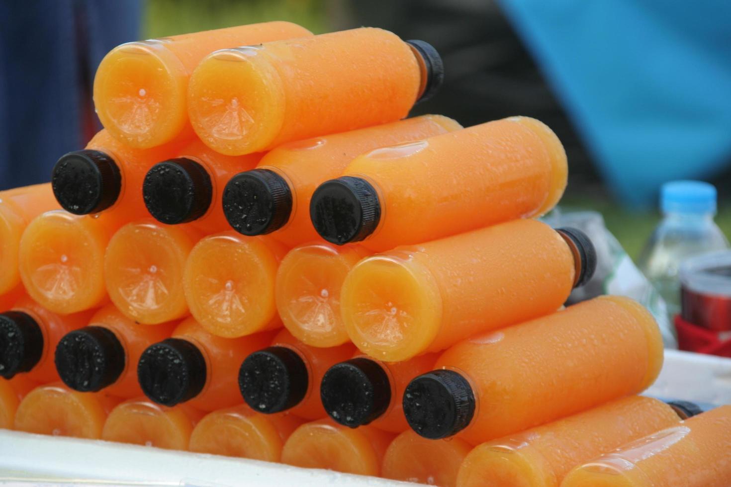 mucchio di bottiglie di succo d'arancia, succo d'arancia in bottiglia di plastica in vendita. foto