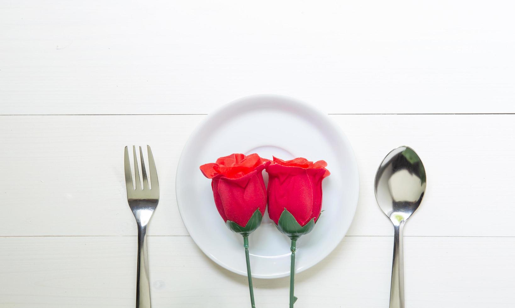 regalo presente con fiore di rosa rossa e piatto e cucchiaio e forchetta sul tavolo di legno, 14 febbraio del giorno dell'amore con copia spazio romantico, concetto di vacanza di San Valentino, vista dall'alto. foto