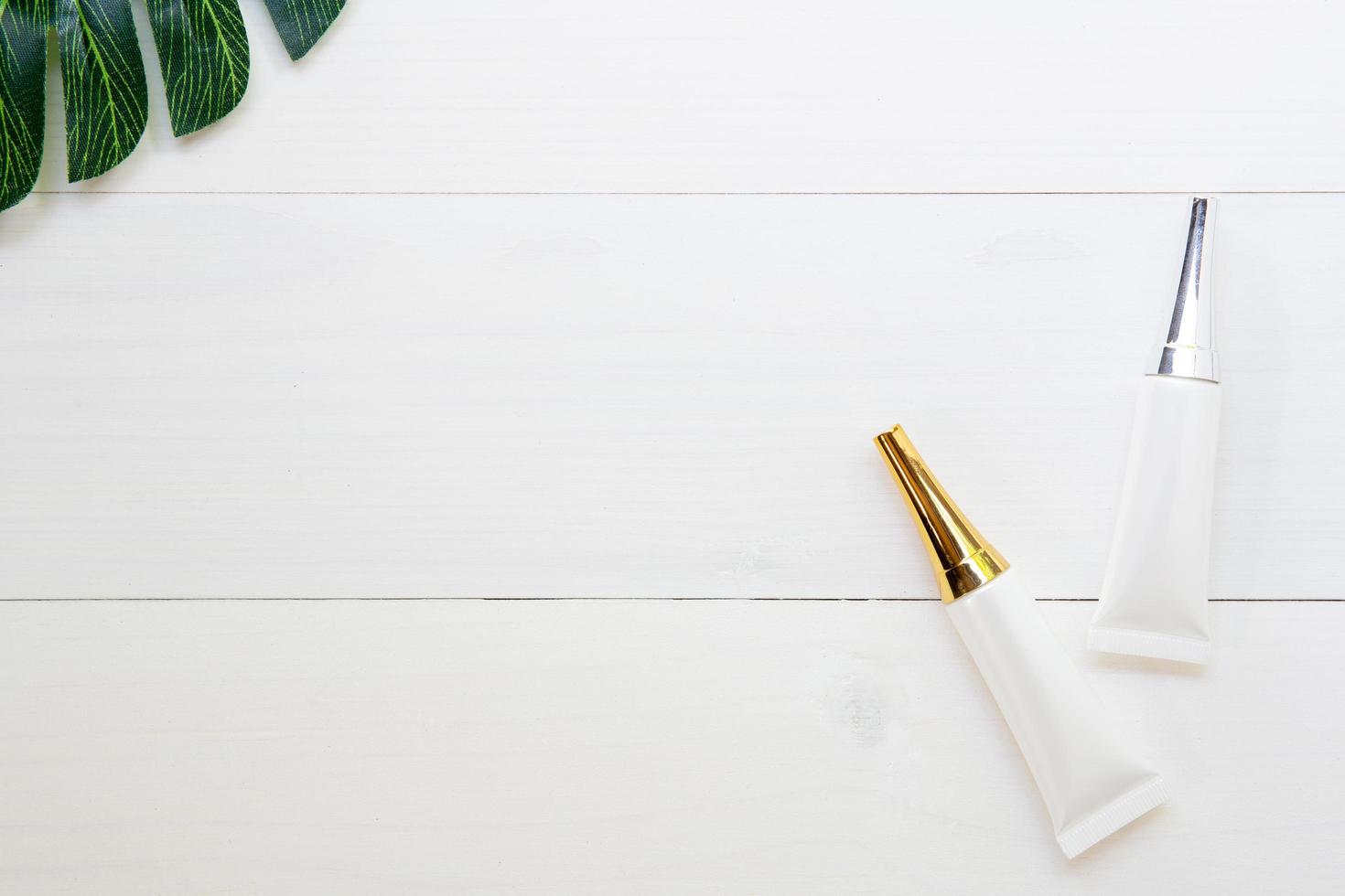 prodotto cosmetico e per la cura della pelle e foglie verdi su tavolo di legno bianco, bellezza con crema per il trattamento e crema idratante su scrivania in legno, concetto di salute e benessere, vista dall'alto. foto