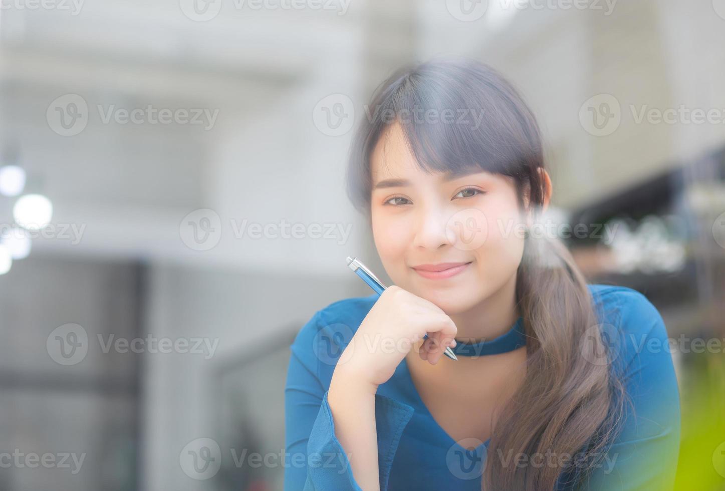 bella giovane scrittrice asiatica sorridente pensando idea e scrivendo su taccuino o diario con felice, lo stile di vita della ragazza asiatica è studente, lavoro di pianificazione femminile, istruzione e concetto di business. foto