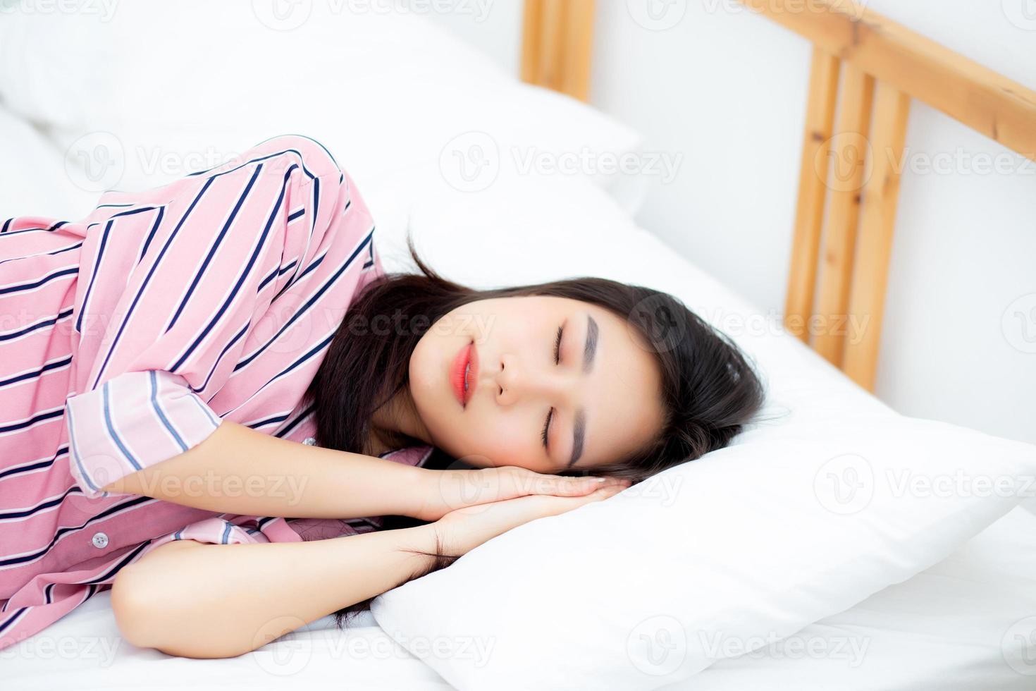 ritratto di bella giovane donna asiatica dormire sdraiato a letto con la testa sul cuscino comodo e felice con il tempo libero, ragazza con relax per il concetto di salute e stile di vita. foto