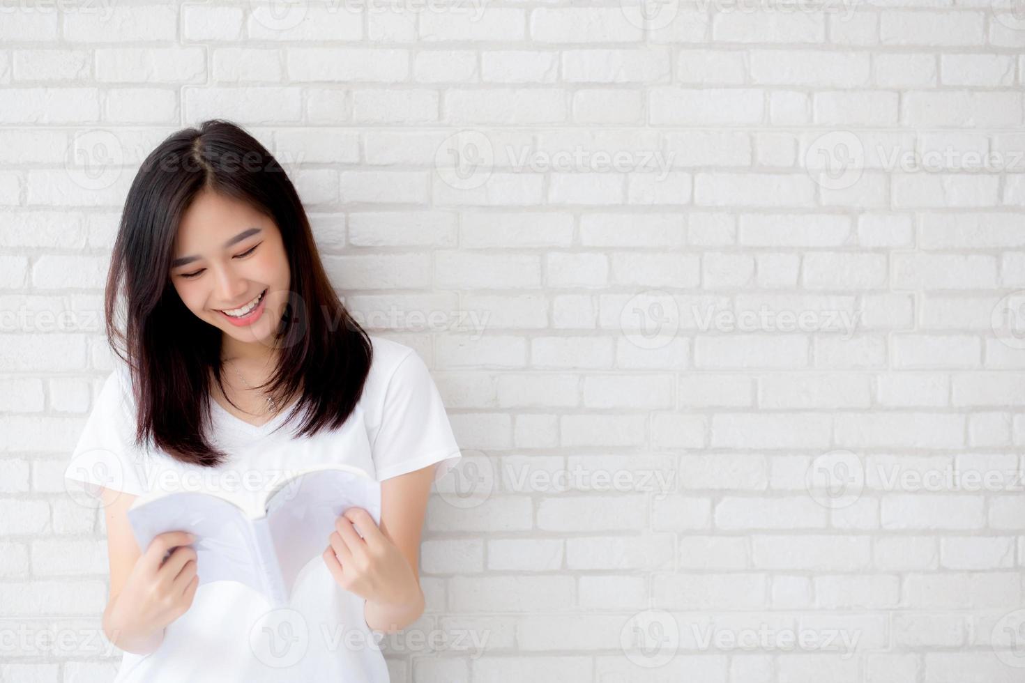 bella del ritratto giovane donna asiatica felicità rilassarsi libro di lettura in piedi su cemento cemento sfondo bianco a casa, ragazza felice contenuto di studio letteratura, educazione e concetto di stile di vita. foto