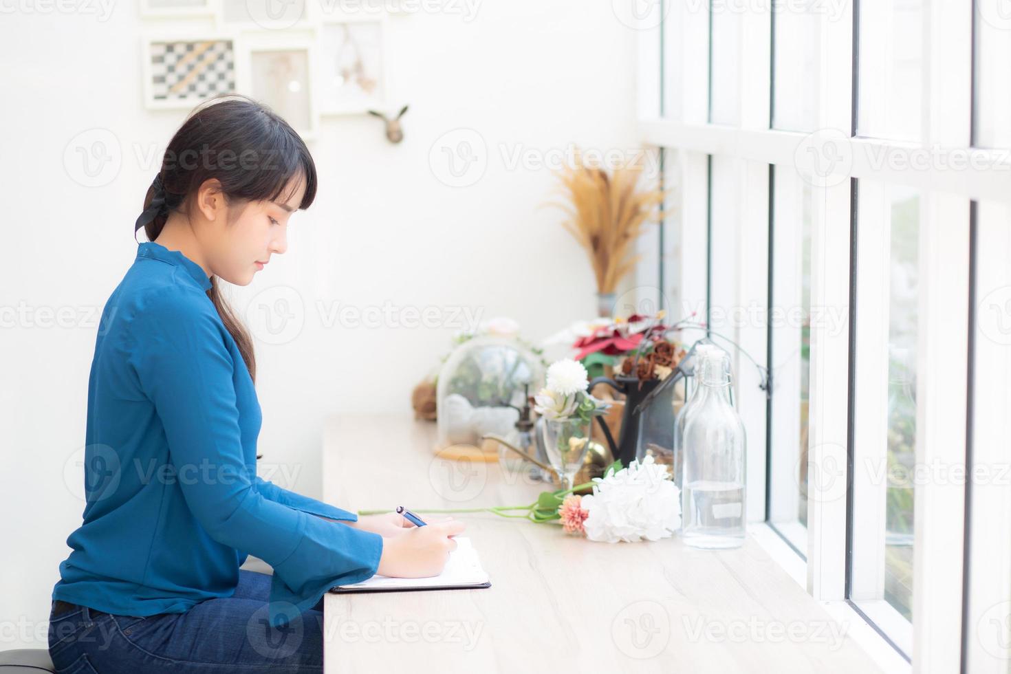 bella scrittrice della giovane donna asiatica del ritratto che scrive sul taccuino o sul diario con felice, lo stile di vita della ragazza asiatica è studente, lavoro di pianificazione femminile, istruzione e concetto di affari. foto