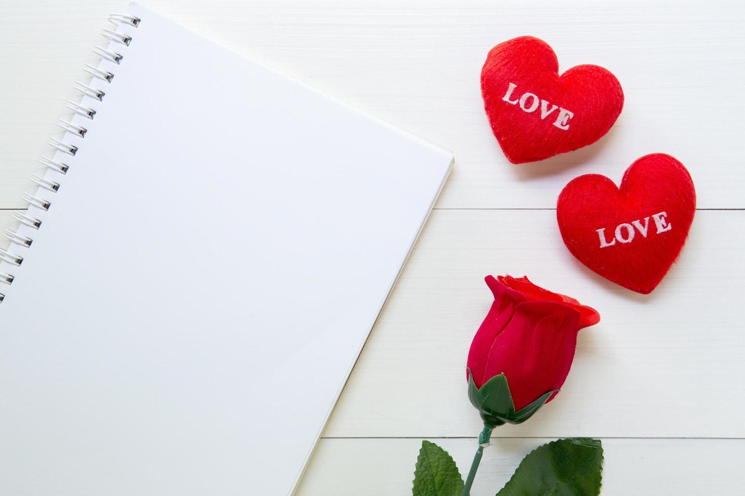 presente fiore di rosa rossa e taccuino e forma di cuore con spazio per la copia sul tavolo di legno, 14 febbraio del giorno dell'amore con romantico concetto di vacanza di San Valentino, vista dall'alto. foto