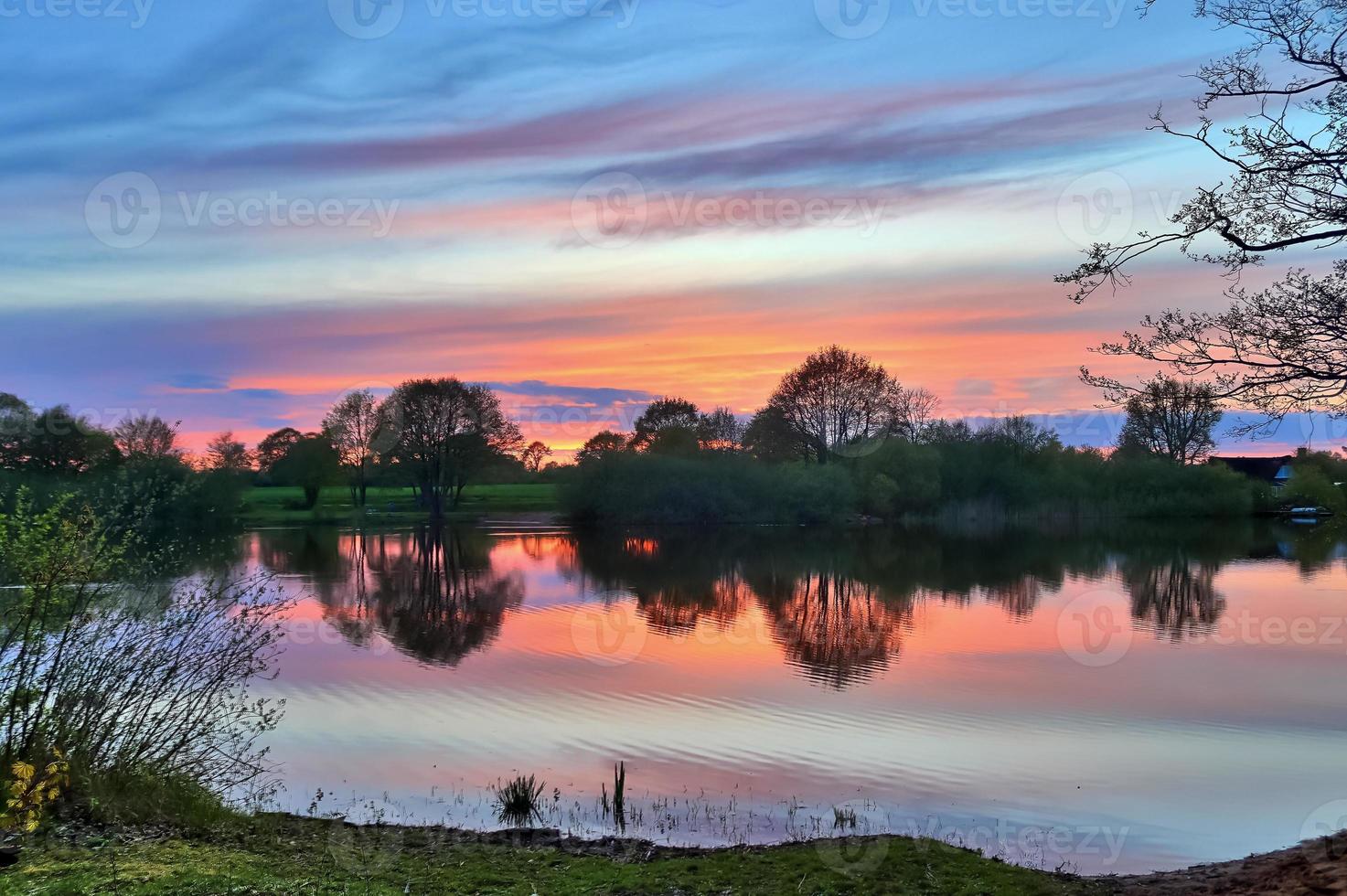 bellissimo paesaggio al tramonto in un lago con una superficie d'acqua riflettente foto