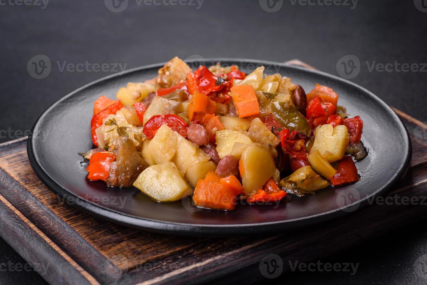 stufato di verdure o ratatouille con melanzane, pomodori, peperoni dolci e piccanti, cipolle, carote e spezie nel piatto foto